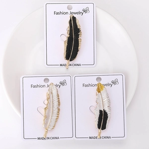 Detailed close-up of feather pins in black and white colors on a jewelry display card