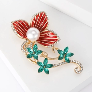 Elegant gold flower brooch with red enamel petals, green crystals and a pearl accent