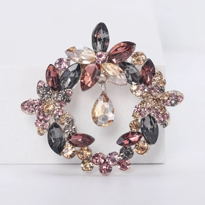 Macro shot of wreath-shaped crystal brooch with heart-drop pendant and floral design