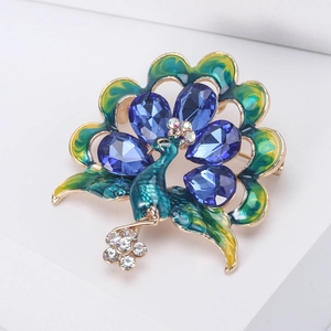 Detail of peacock brooch with blue crystal droplets and colorful enamel on a gold base