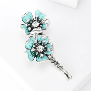 Detail of vintage flower brooch featuring blue enamel petals and sparkling rhinestones