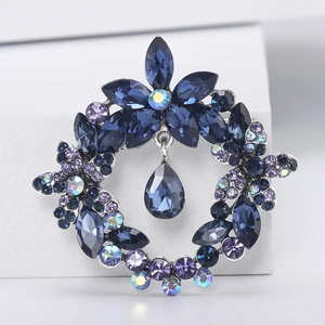 Macro shot of a floral crystal wreath brooch with deep blue pear-cut stones and silver base