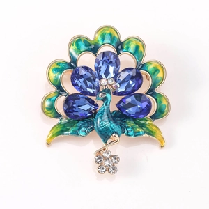 Detailed peacock brooch featuring blue teardrop gems and vibrant green enamel inlays
