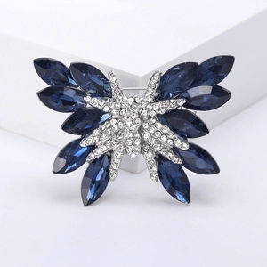Spilla a farfalla in cristallo blu scintillante con strass su un cubo bianco pulito