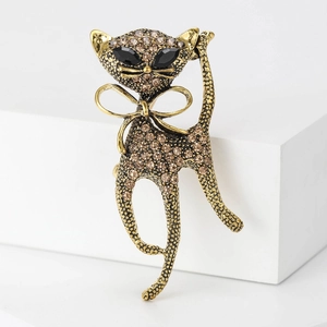 Macro detail of a vintage gold-toned cat brooch with amber rhinestones and black gem eyes