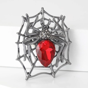 Macro shot of spider web brooch with dark silver metal and teardrop red gemstone