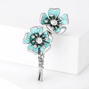 Elegant silver flower brooch with blue enamel and sparkling rhinestones on white display