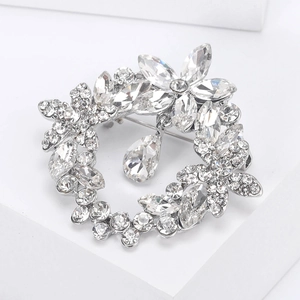 Macro detail of silver floral wreath brooch with sparkling crystals and waterdrop pendant