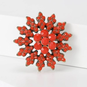 Macro detail of snowflake brooch with red faceted beads and vintage bronze finish
