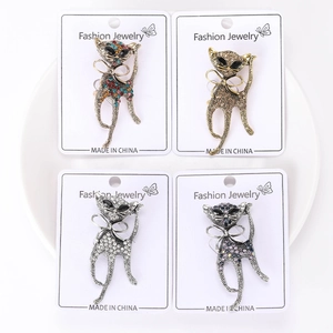 Close-up of four rhinestone cat brooches in various colors on jewelry display cards
