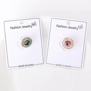 Detail of round gold pins with emerald and pink stones surrounded by sparkling zircons