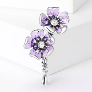 Elegant purple flower brooch with enamel petals and crystal stamens on a white pedestal