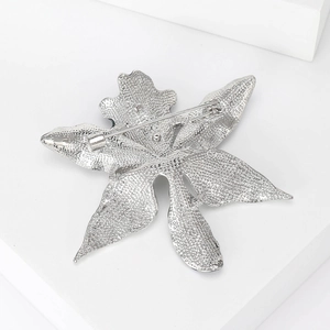 Silver flower brooch back view showing detailed alloy texture and secure pin clasp on white base