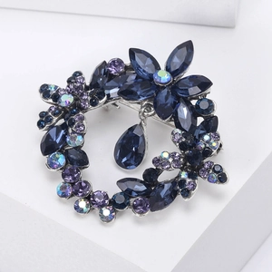 Detailed close-up of a floral wreath brooch with blue crystal drop and silver alloy