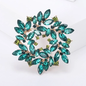 Detail of elegant gold wreath brooch with green crystals and sparkling leaf design