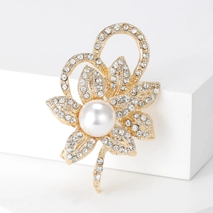 Détail d'une broche fleur avec perle blanche et pétales de cristal sur fond blanc