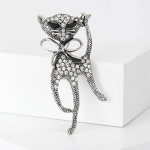 Macro detail of a silver cat brooch featuring sparkling crystals and a bow tie accent