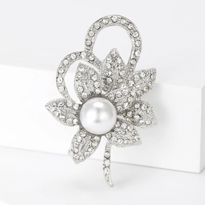 Gros plan d'une broche fleur en argent avec strass scintillants et une grande perle centrale