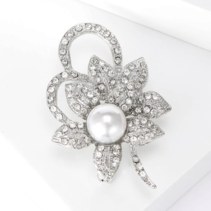 Gros plan sur une broche fleurie avec strass brillants et une perle blanche centrale