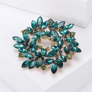 Detailed macro view of an elegant wreath brooch with deep green rhinestones on stone base