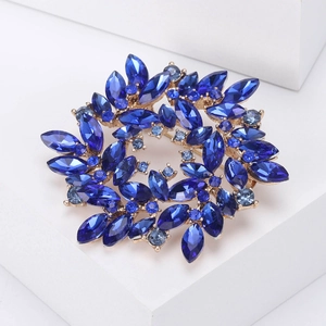 Detailed close-up of a blue rhinestone flower wreath brooch on a white stone base