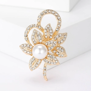 Élégante broche fleur dorée avec strass scintillants et perle centrale sur support blanc