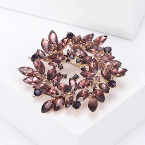 Macro detail of luxury floral wreath brooch with purple crystals and gold-plated base