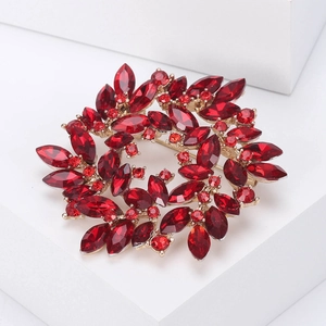 Detailed view of red rhinestone wreath brooch with golden alloy setting and faceted stones