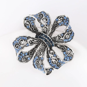 Détail macro d'une broche ruban vintage en argent avec cristaux bleus et gravures