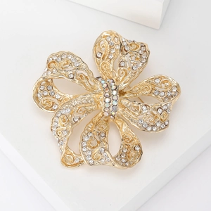 Détail d'une élégante broche nœud dorée sertie de cristaux et nacre de coquille