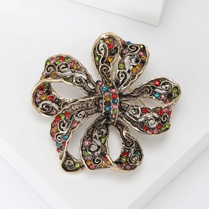 Détails de la broche vintage dorée avec strass colorés et ornements en filigrane