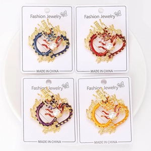 Detail of four colorful dragon brooches with enamel finish and imitation pearls