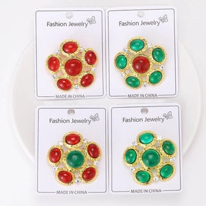 Detailed macro view of four floral brooches with red and green glass stones in gold frames