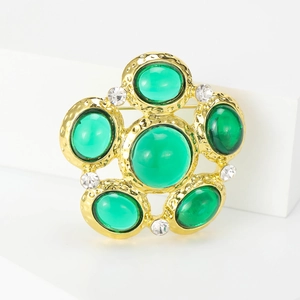 Detail of vintage palace style gold brooch with green cabochon gems and small white crystals