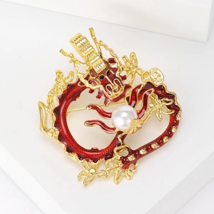 Detail of red enamel dragon brooch with golden metal casting and white pearl center