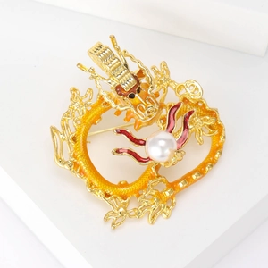 Detailed close-up of a dragon brooch with vibrant orange enamel and a lustrous central pearl