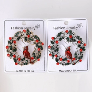 Detail of Christmas wreath brooches with red rhinestone birds and green oil drip enamel