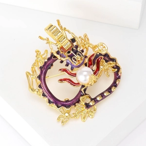Detail of a golden dragon brooch with purple enamel and a white pearl on a white pedestal