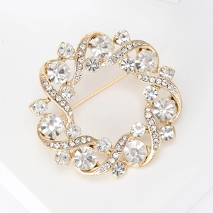 Détail de la broche couronne dorée sertie de strass brillants sur un fond blanc pur