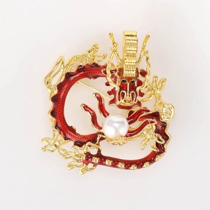 Detailed close-up of a gold dragon brooch with red enamel and a large white pearl