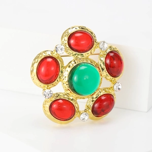 Elegant vintage flower brooch with green center stone and red petals in gold finish