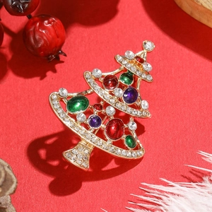 Broche sapin de Noël en alliage doré avec strass colorés sur fond rouge festif