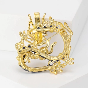 Golden dragon brooch with intricate scales and blue enamel detail on a modern stone display
