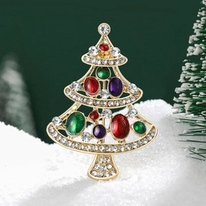 Vue détaillée de la broche sapin de Noël émaillée avec gemmes sur un fond de neige