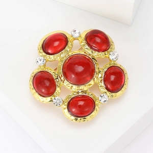 Macro detail of a vintage court style gold brooch with red cabochon stones and white crystals