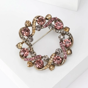 Vue macro de la broche couronne vintage avec cristaux champagne sur un support blanc