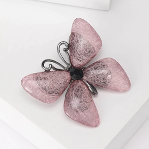 Detailansicht der Schmetterlingsbrosche mit rosa Flügeln und schwarzem facettiertem Stein