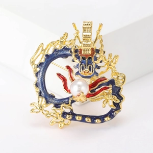 Golden dragon brooch with colorful enamel and a white pearl on a clean white background
