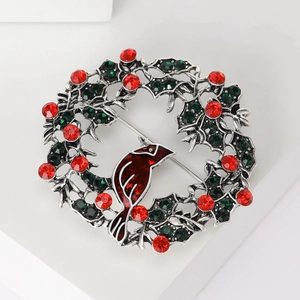 Detail of Christmas wreath brooch with green rhinestones and red enamel bird on alloy base