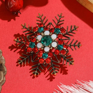 Elegant snowflake brooch with vintage gold base and colorful rhinestones on red backdrop